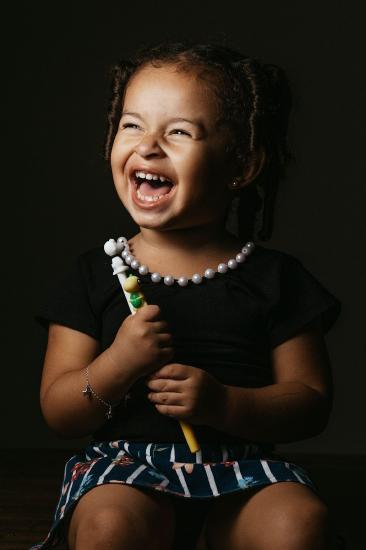 Young girl with a very big, happy smile: mouth open, eyes slightly shut.