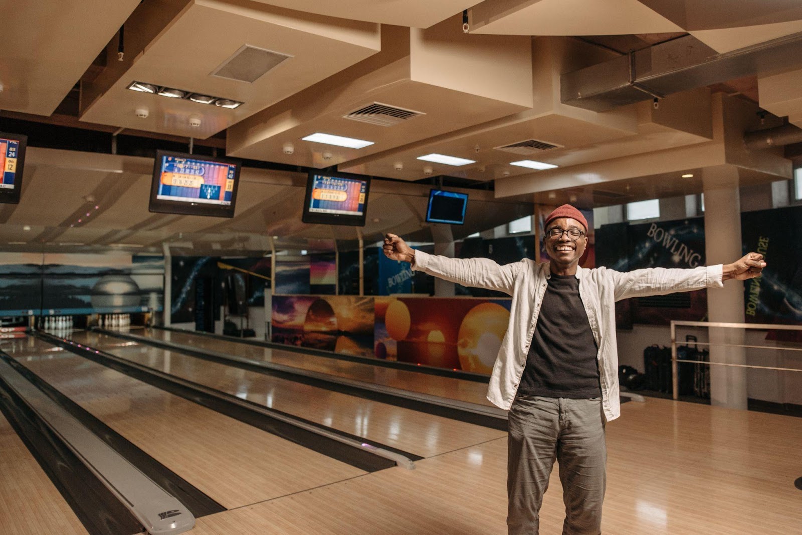 A man with outstretched arms and a big smile on his face in a bowling alley