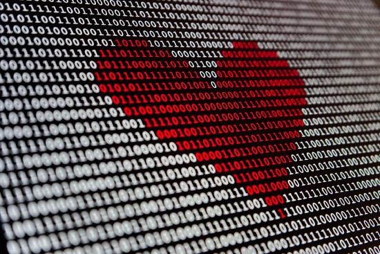 White binary code on a computer screen, with a red heart superimposed