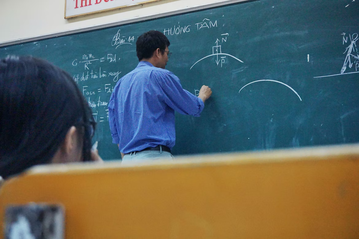 Man writing physics formulas on chalkboard