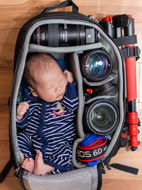 An infant inside a camera bag