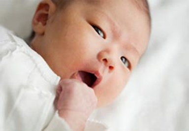 Un bebé moviéndose una mano a su boca