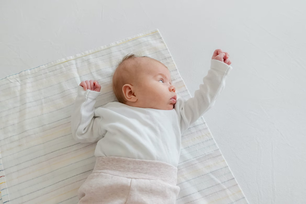 The asymmetrical tonic neck reflex in a two-week-old infant. left arm bent at elbow hand pointed up right arm extended out in air. 