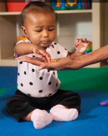 Nine month old infant using the pincer grasp by picking an item up with thumb and point finger