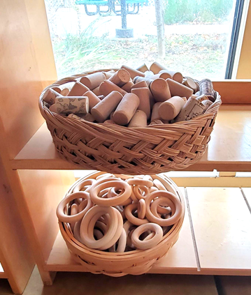 Play materials stored in open baskets on a low shelf. 