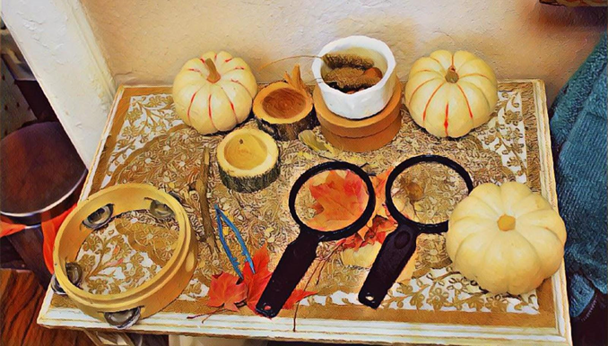small pumpkins, magnifying glasses and tambourine on table. 