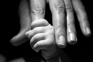 Infant grasping onto an adult’s finger