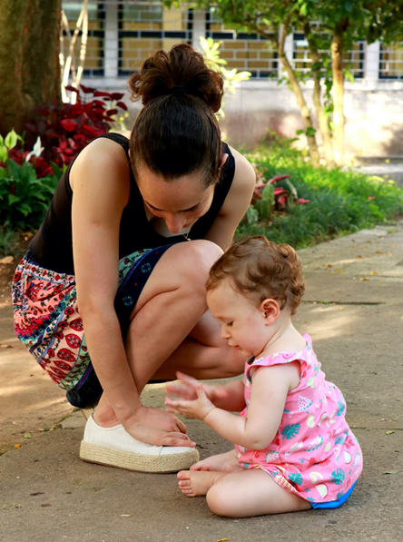 Caregiver crouching next to toddler with interest