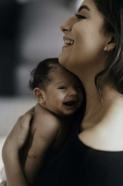 Smiling mother holds smiling infant to chest