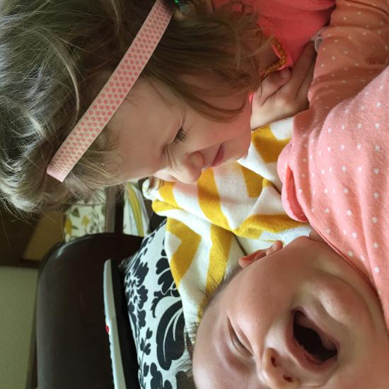 Infant crying and toddler making silly face