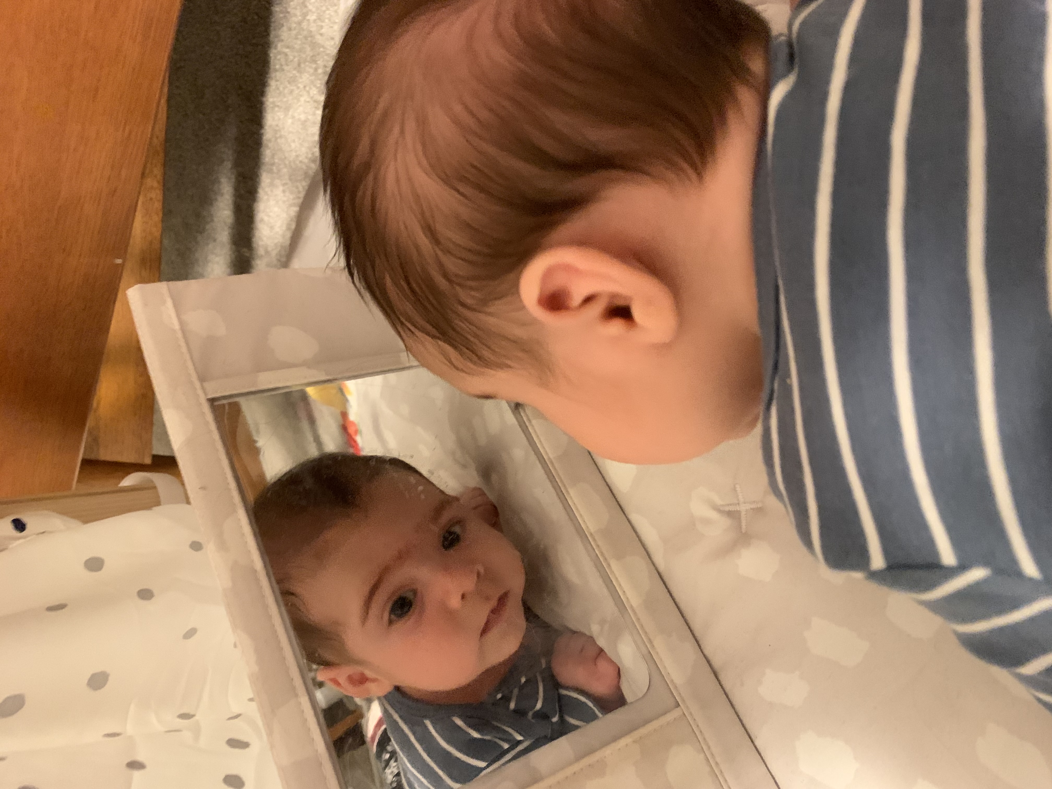 Bebé joven mirando a cuidador en reflejo espejo