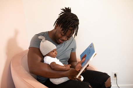 male with infant in lap reading