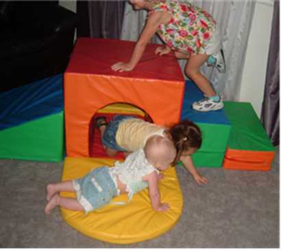 Infant, toddler and young preschooler climbing on large foam blocks
