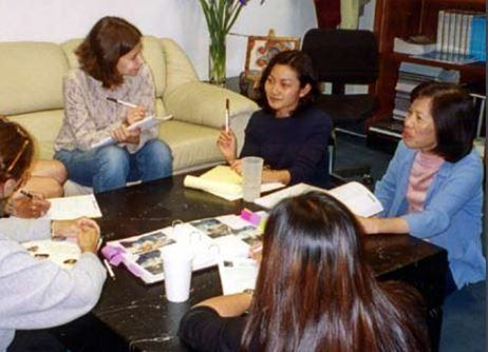 Adults sitting around a table with notbooks in front of them. 
