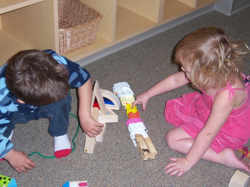 Dos niños pequeños uno frente al otro jugando con diferentes bloques