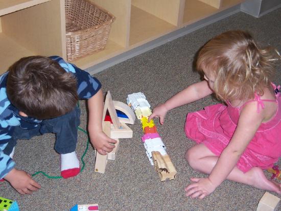 Two toddler facing each other each playing with different blocks