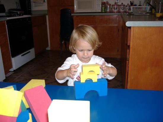 Toddler sits alone playing with blocks