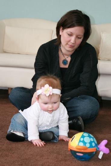 Caregiver looks as infant plays with toy