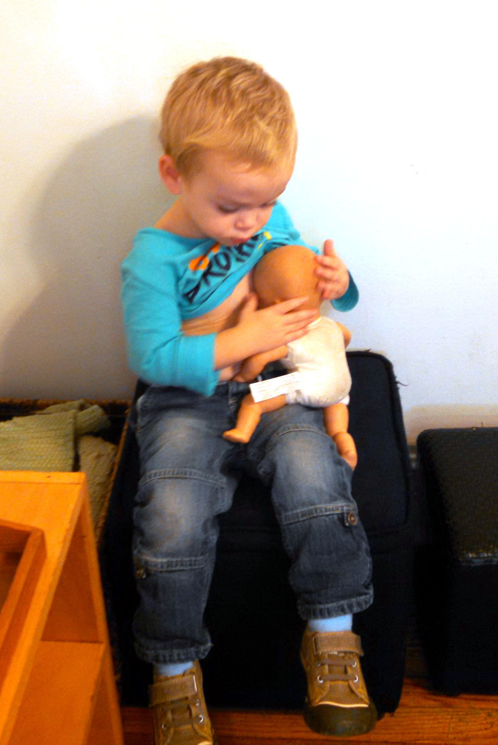 Un niño jugando, amamantando a su muñeca