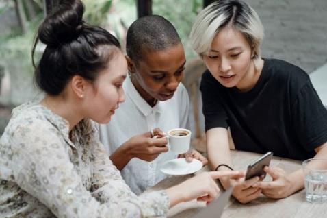 A group of people looking at a phone

Description automatically generated with medium confidence