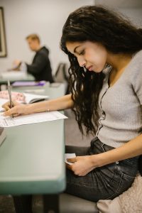 Mujer haciendo trampa en el examen con papel debajo del escritorio