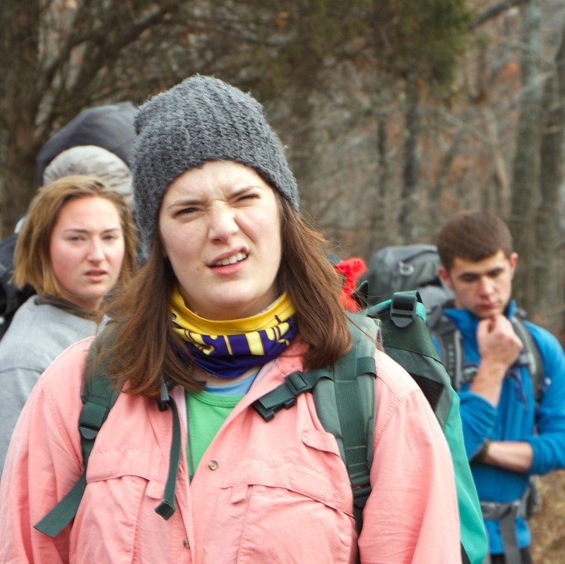 A group of hikers are stopped in the middle of a trail with confused looks on their faces.