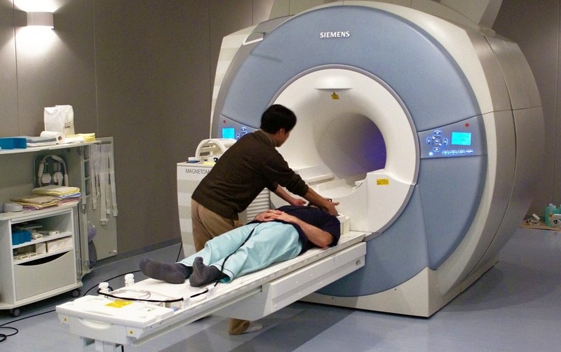 A researcher is preparing to secure the head coil over a participant going into an MRI machine. 