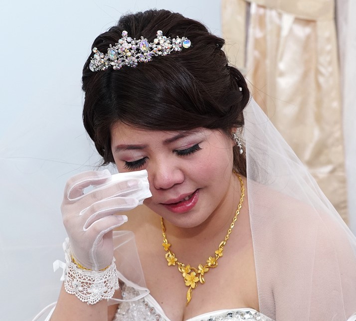 A bride wipes tears from her eyes.